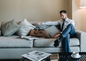 a man in a suit and tie sitting on a couch with a laptop at JW Marriott Hotel & Suites Saigon, The Apartments in Ho Chi Minh City