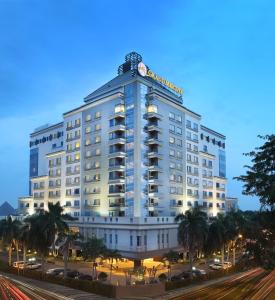 un gran edificio blanco con palmeras delante en Grand Mercure Medan Angkasa, en Medan