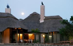 un edificio con tetto di paglia, tavoli e sedie di Premier Resort Mpongo Private Game Reserve a Macleantown