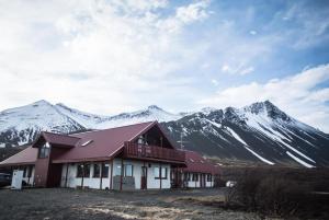 a house with snow covered mountains in the background at Hotel Hafnarfjall in Borgarnes