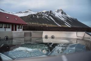 bañera de hidromasaje frente a una montaña nevada en Hotel Hafnarfjall en Borgarnes