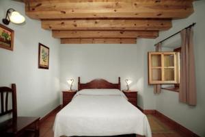 a bedroom with a white bed and wooden ceilings at Casa Rural Soportales de Peguerinos in Peguerinos