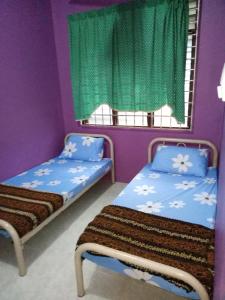 2 camas en una habitación con paredes moradas en Syahril homestay, en Dungun