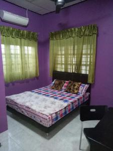 ドゥングンにあるSyahril homestayの紫の壁と窓が特徴のベッドルーム1室