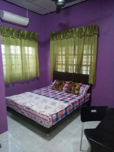 a bedroom with a bed with purple walls and windows at Syahril homestay in Dungun