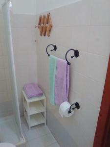 a bathroom with purple and green towels and a shelf at Albergo Cavour SELF CHECK-IN in Livorno