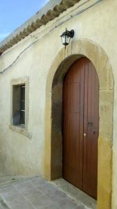 - un bâtiment avec une porte en bois éclairée au-dessus dans l'établissement Tipica casa d'altri tempi, à Furnari