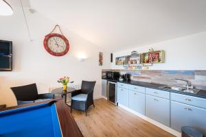 a kitchen with blue cabinets and a clock on the wall at Driftwood in Bude