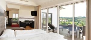 1 Schlafzimmer mit einem Bett und einem Balkon mit Aussicht in der Unterkunft BURGHOF - DAS HOTEL in Brombachtal