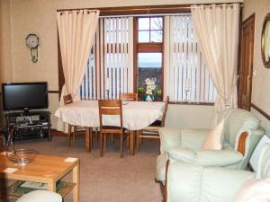 a living room with a couch and a table and a television at Anchorage B&B in Cockenzie