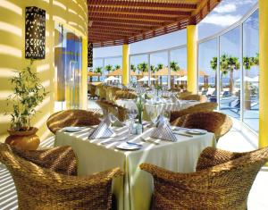 ein Restaurant mit weißen Tischen und Stühlen und Fenstern in der Unterkunft Pueblo Bonito Pacifica Golf & Spa Resort - All Inclusive - Adults Only in Cabo San Lucas