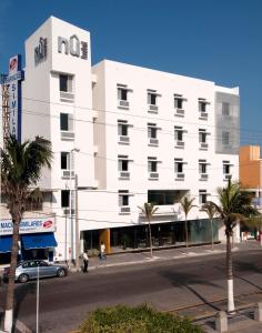 a white building on a city street with palm trees at Nu Hotel in Veracruz