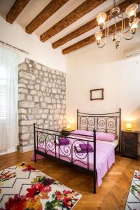 um quarto com uma cama roxa e uma parede de pedra em Old Palace Apartment em Dubrovnik