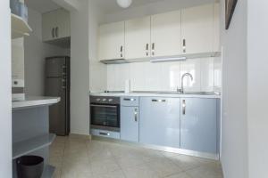 cocina con armarios blancos, fregadero y nevera en Apartment Lucija en Dubrovnik