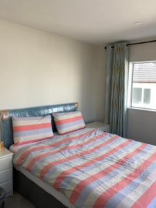 a bedroom with a bed with a striped comforter and a window at Brand new bedroom in Karaka (Auckland) in Auckland