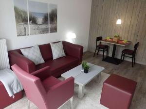 Una sala de estar con un sofá rojo y una mesa. en dat geele hus Wohnung Nr. 4, en Büsum