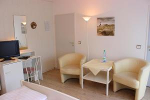 une petite chambre avec deux chaises, une table et une télévision dans l'établissement Hotel Garni La mer, à Bad Zwischenahn