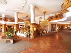 a large lobby with a staircase and chandeliers at Interalpen-Hotel Tyrol in Buchen