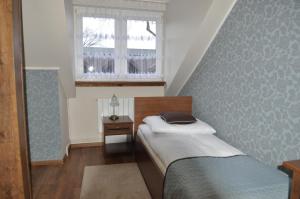 a small bedroom with a bed and a window at Dworek Biała Dama in Nieborów