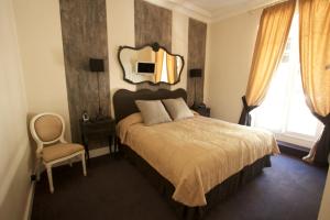 een slaapkamer met een bed met een spiegel aan de muur bij Hotel De Monaco in Cap d'Ail