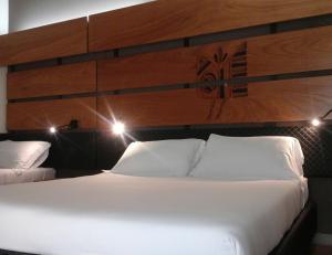 una camera da letto con un grande letto bianco con testiera in legno di Hotel I Narcisi a Siniscola