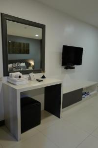 a desk with a mirror and a television in a room at At Sakon Hotel in Sakon Nakhon