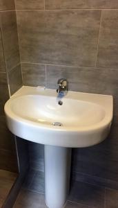 un lavandino bianco in un bagno con parete di Four Stars Hotel a Londra