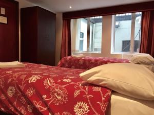 a bedroom with a red and white bed with a window at Four Stars Hotel in London