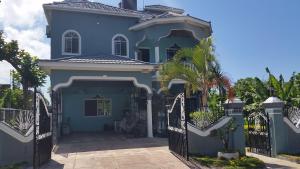 a blue house with a gate and a palm tree at Bailey's Bed and Breakfast in Runaway Bay