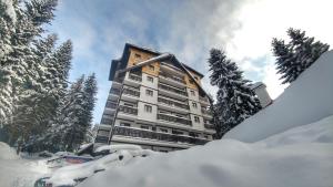 un gran edificio de apartamentos con árboles en la nieve en Apartments Zed Vila Zvoncica en Kopaonik