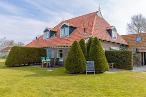 a house with hedges and a sign in front of it at State Klaver Vier in Hollum