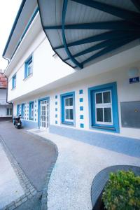 a white building with blue windows and a sidewalk at Apartma City & Free Parking in Ljubljana