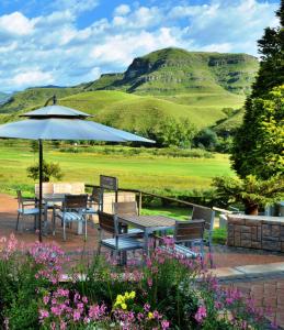 uma mesa e cadeiras com um guarda-sol e flores em Premier Resort Sani Pass em Himeville