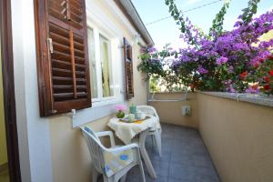 a small table and chairs on a balcony with flowers at House Orhideja in Mali Lošinj