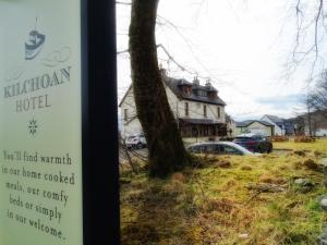 a sign in front of a house with a tree at Kilchoan Hotel in Kilchoan