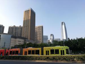 a yellow train in a city with tall buildings at Guangzhou Convention Center Apartment in Guangzhou