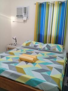 ein Schlafzimmer mit einem Bett mit einer bunten Bettdecke in der Unterkunft Mingche Apartment in Panglao