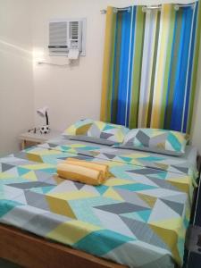 a bedroom with a bed with a colorful comforter at Mingche Apartment in Panglao