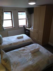 a bedroom with two beds and a desk and two windows at Tollyrose Country House in Newcastle