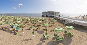 a beach with many chairs and umbrellas and a pier at Appartamento Via Rieti in Senigallia