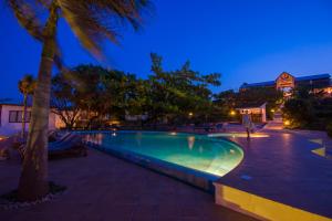 a swimming pool at night with a palm tree at Warere Beach in Nungwi