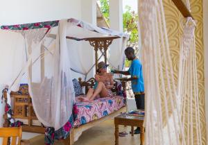 a woman sitting on a bed in a room at Warere Beach in Nungwi