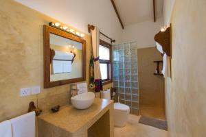 a bathroom with a sink and a toilet and a mirror at Warere Beach in Nungwi