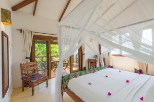 a bedroom with a white bed and a chair at Warere Beach in Nungwi