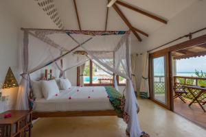 Schlafzimmer mit einem Himmelbett und Meerblick in der Unterkunft Warere Beach in Nungwi