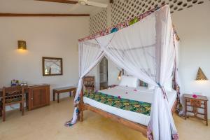 a bedroom with a bed with a canopy at Warere Beach in Nungwi