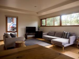 een woonkamer met 2 banken en een tv bij Freycinet Studios "Nook" in Coles Bay