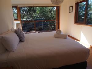 een groot wit bed in een kamer met een groot raam bij Freycinet Studios "Nook" in Coles Bay