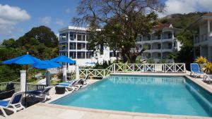una piscina con sedie e ombrelloni accanto a un hotel di Bacolet Beach Club a Scarborough