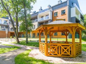 un cenador de madera en un parque frente a un edificio en DWIE SOSNY Apartament 52, en Ustronie Morskie